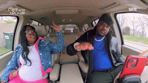 A man and woman are sitting in a car, playfully dancing and waving their hands to the music. Both seem to be enjoying the moment, with the woman enthusiastically gesturing while the man grooves along, creating a fun and carefree vibe. The scene is from the show "Love After Lockup."